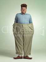 Diet progress. Shot of an overweight man wearing a pair of oversized pants looking pleased.