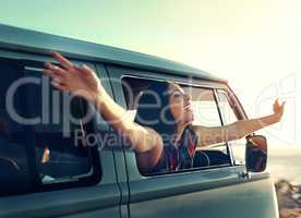 Life is the greatest road worth traveling. Shot of a young woman leaning out of her vans window with her arms outstretched.