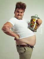This will help me grow nice and big. Cropped shot of an overweight man holding a large jar of candy.