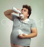 My diet said I need to eat light foods. Shot of an overweight man filling his mouth with whipped cream.