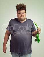 Nope, dont want it. Shot of an unhappy overweight man holding a celery stick.