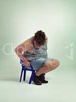 Did I get bigger or the chair smaller. Shot of an overweight man trying to fit into a small chair.