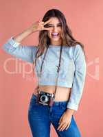 Lets have fun, make memories and capture them. Studio shot of a beautiful young woman posing with a vintage camera against a pink background.