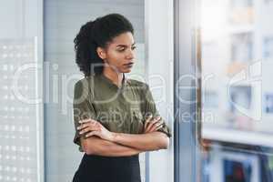 Never let fear or self-doubt cloud your judgment. Shot of a young businesswoman looking out of a window in her office.