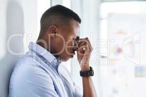 Let me take a minute to think clearly. Shot of a young and stressed businessman suffering from a headache while trying to work in the office.