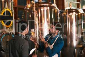 Its all about the flavor. Shot of two young working men doing inspection of their beer making machinery inside of a beer brewery during the day.