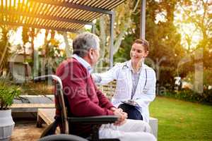 Walking the road to recovery together. Shot of a young doctor and her elderly patient talking while sitting outside.