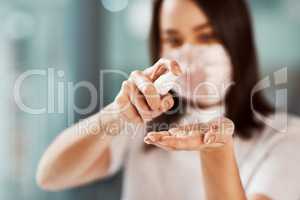 Hand sanitiser kills many harmful germs that could infect your colleagues. Closeup shot of a businesswoman using hand sanitiser in an office.