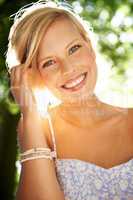 Shining as brilliantly as the sun. Portrait of a beautiful young woman standing in a sunlit forest.