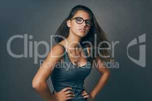 Channel your inner nerd. Studio shot of an attractive young woman striking a pose against a grey background.