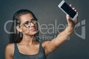 Your smile is the best filter you have. Studio shot of an attractive young woman taking a selfie against a grey background.