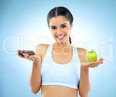 Healthy is a choice. Studio shot of a woman deciding between healthy and unhealthy foods.