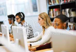 We are more prepared than ever. Shot of a group young students working on computers and making notes in a library.