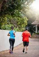 Getting a worthwhile full-body workout. Rearview shot of a couple out for a run.