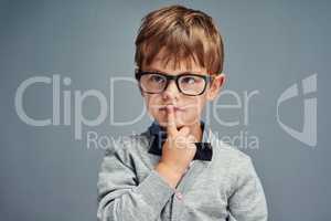 Question everything. Studio shot of a smartly dressed little boy looking thoughtful against a gray background.