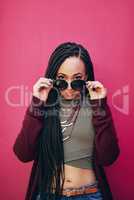 My life, my style. Portrait of a young woman with braids posing against a pink background.