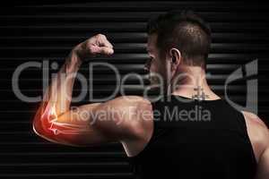 Pain is just a part of the package. Rearview shot of an athletic young man flexing with an elbow injury in the studio.