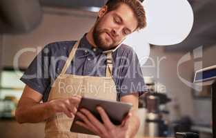 Make sure your online presence is all it can be. Shot of a young man using a digital tablet while working in a coffee shop.