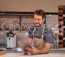 Sending out special offers to all my existing customers. Shot of a young man using a digital tablet while working in a coffee shop.