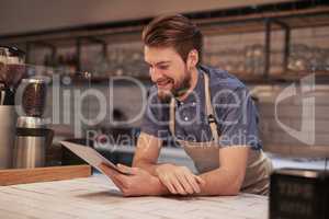 Creating inexpensive online advertisements to target local audiences. Shot of a young man using a digital tablet while working in a coffee shop.