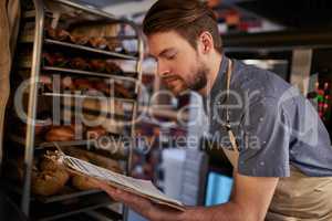 Making sure everything is baked to perfection. Shot of a young business owner counting his baked goods.