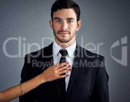 Success is the ultimate aphrodisiac. Studio portrait of a handsome young businessman being touched by an unrecognizable womans hand against a gray background.