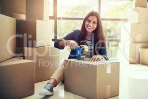 I cant wait to move into my dream home soon. Portrait of a young woman packing boxes while moving house.