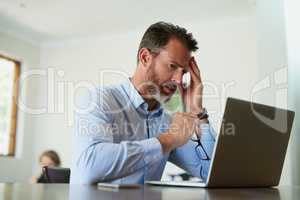 When work stress invades home life. Shot of a mature businessman looking stressed while using a laptop to work from home.