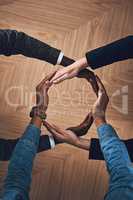 There is more power in unity than division. High angle shot of a group of unidentifiable businesspeople forming a circle with their hands.