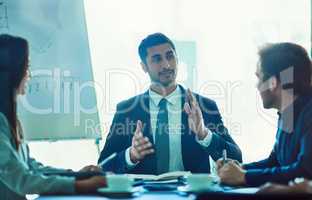 Owning the boardroom. Shot of a young executive talking during a meeting with colleagues in a boardoom.