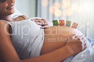 Im so ready to be a mom. Cropped shot of a pregnant woman with wooden blocks on her belly that spell the word baby.