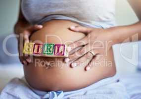 Getting the gift of a little girl. Cropped shot of a pregnant woman with wooden blocks on her belly that spell the word girl.