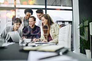 Business driven by the world online. Cropped shot of a group of businesspeople working together on a laptop in a modern office.