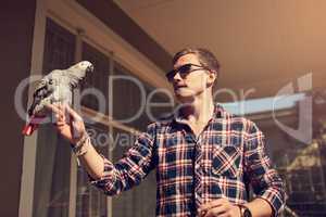 You cant tame the truly free. Shot of a young man and an African Gray perched on his hand.