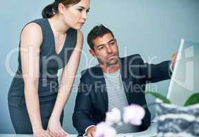 They always pay attention to the details. Shot of two coworkers working together at a computer in an office.