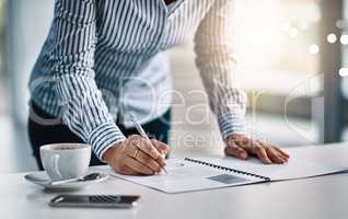 Proper planning is vital for any business. Closeup shot of an unrecognizable businesswoman writing notes on a document in an office.