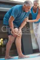 Pain is only temporary. Shot of a mature man grabbing his leg in pain after an intense workout with his wife.