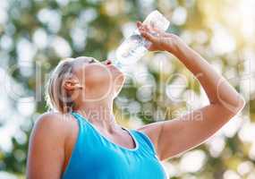 Always stay hydrated during your workouts. Low angle shot of a mature woman drinking water out of a bottle outdoors.