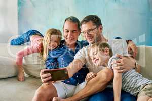 Get in here, were taking a selfie. Cropped shot of an affectionate family of four taking selfies on the sofa at home.