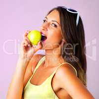 An apple a day fixes everything. Studio shot of a young woman eating an apple against a pink background.
