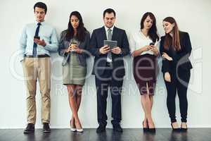 Wireless entertainment while they wait. Studio shot of a group of businesspeople using wireless technology while standing in line.