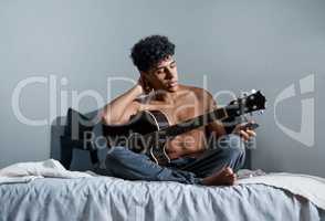 Youre not a musician until youve written a breakup song. Shot of a young man using a smartphone while playing the guitar at home.