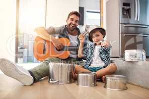 Are you ready for an encore. Portrait of a happy father accompanying his young son on the guitar while he drums on a set of cooking pots.
