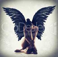 Poise in the stillness. Shot of of naked woman with wings spreading out behind her back.