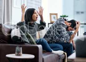 Marriage is the ultimate team sport. Shot of a young couple looking upset while watching tv together at home.