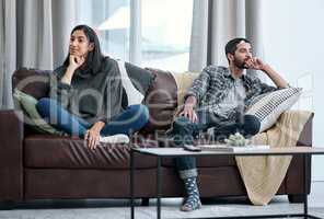 The silent treatment isnt the solution. Shot of a young couple sitting on the sofa and ignoring each other.