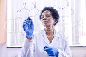 Testing some of her ideas. Shot of a female scientist drawing molecular structures on a glass wall in a lab.