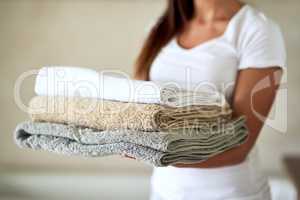 Fluffy comforts. Shot of an unidentifiable woman holding a pile of clean towels.