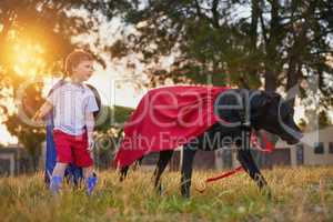 Theyre making headlines. Shot of a little boy and his dog wearing capes while playing outside.