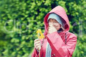 The pollen is making me sneeze. Cropped shot of a young woman smelling a flower and sneezing outdoors.